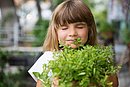Mädchen riecht mit geschlossenen Augen an Kräutern.