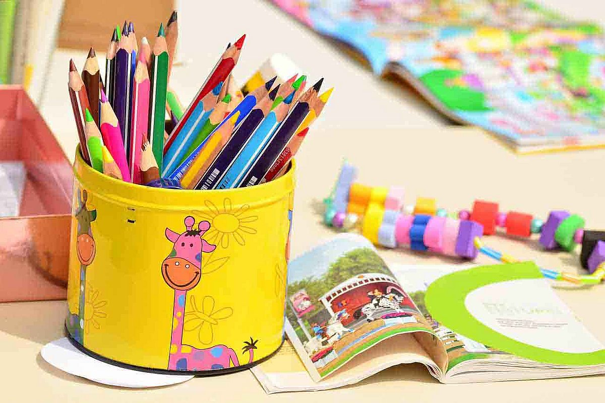 Szene einer Kita - ein bunter Tisch mit Malutensilien, Büchern, Spielzeug