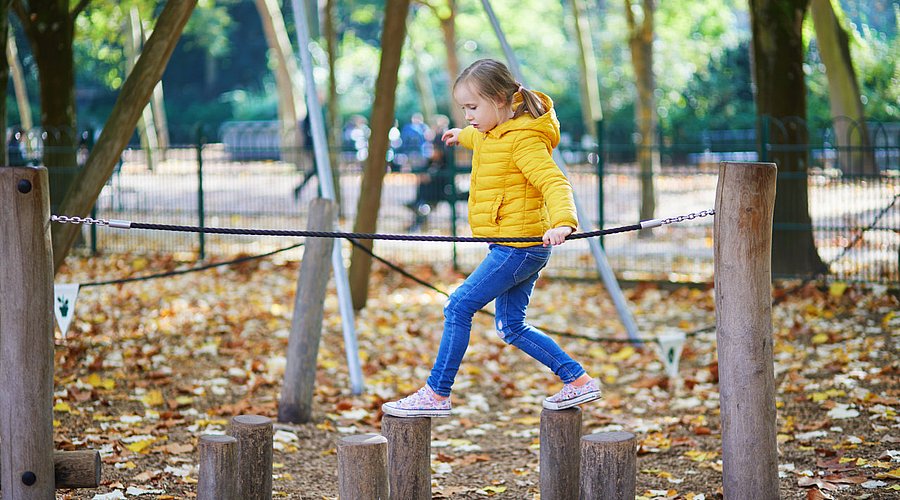 Ein Mädchen balanciert auf einem Spielgerät.