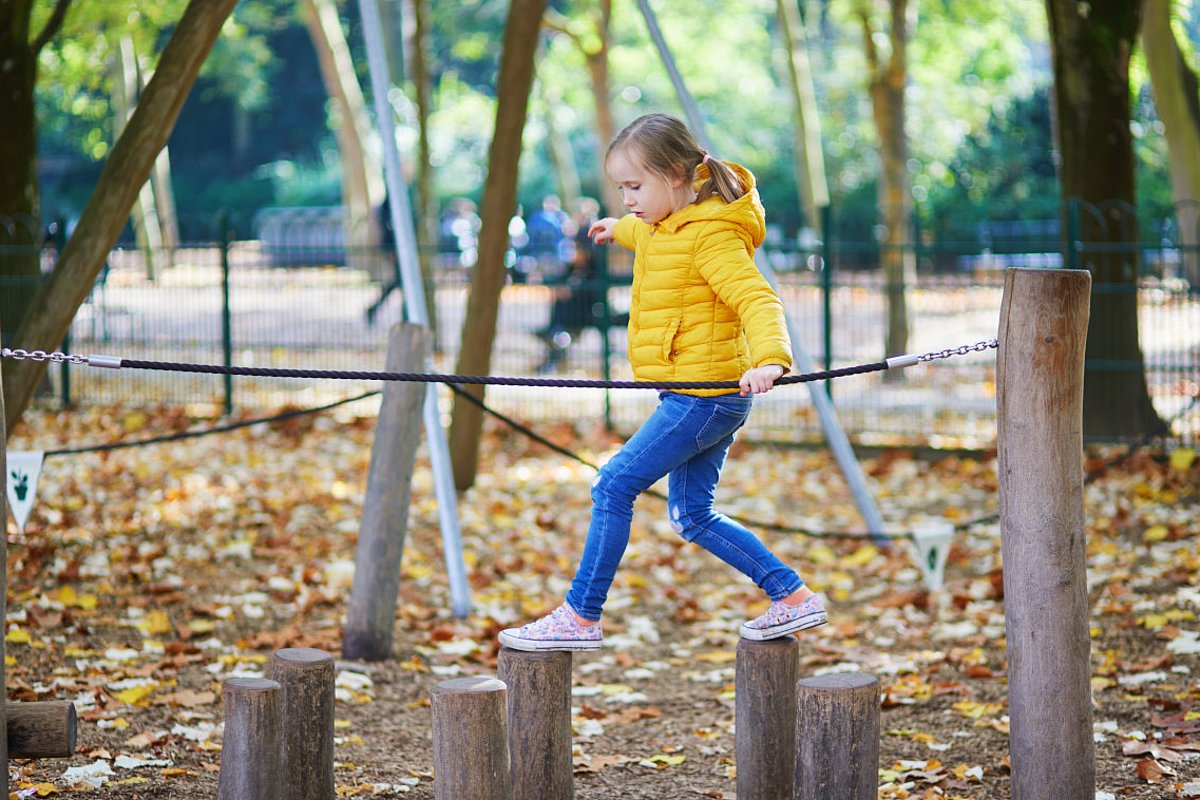 Ein Mädchen balanciert auf einem Spielgerät.