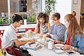 Jugendliche sitzen in der Schulmensa am Tisch.