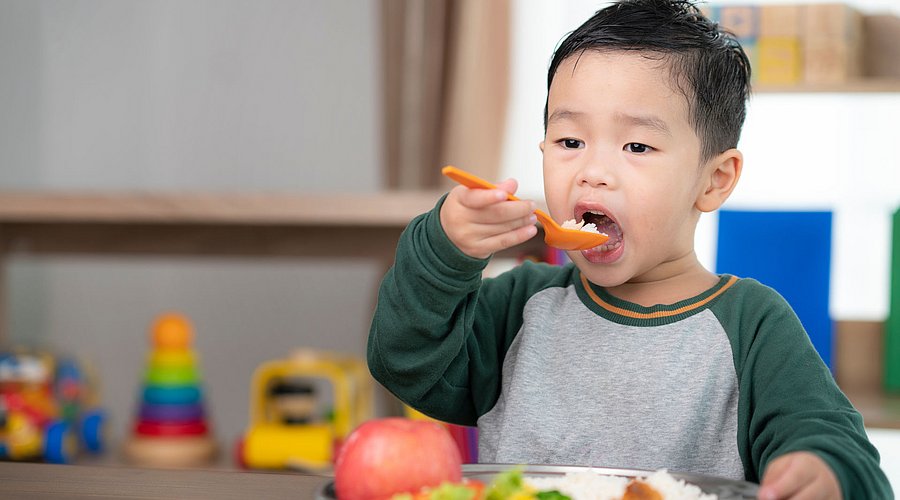 Ein Schulkind isst sein Mittagessen. 