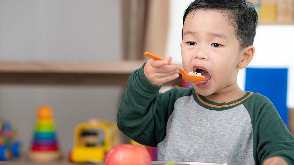 Ein Schulkind isst sein Mittagessen. 
