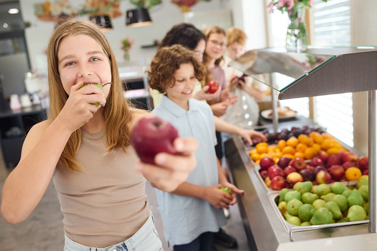Schülerin bedient sich in der Mensa an einer Obst-Bar. 