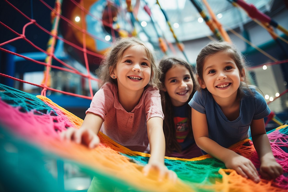 Gruppe fröhlicher Mädchen, die auf dem Schulhof mit Netzkletterseilen spielen.