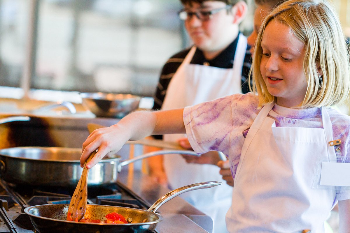 Schulkinder bereiten in einer Lehrküche Essen zu. 