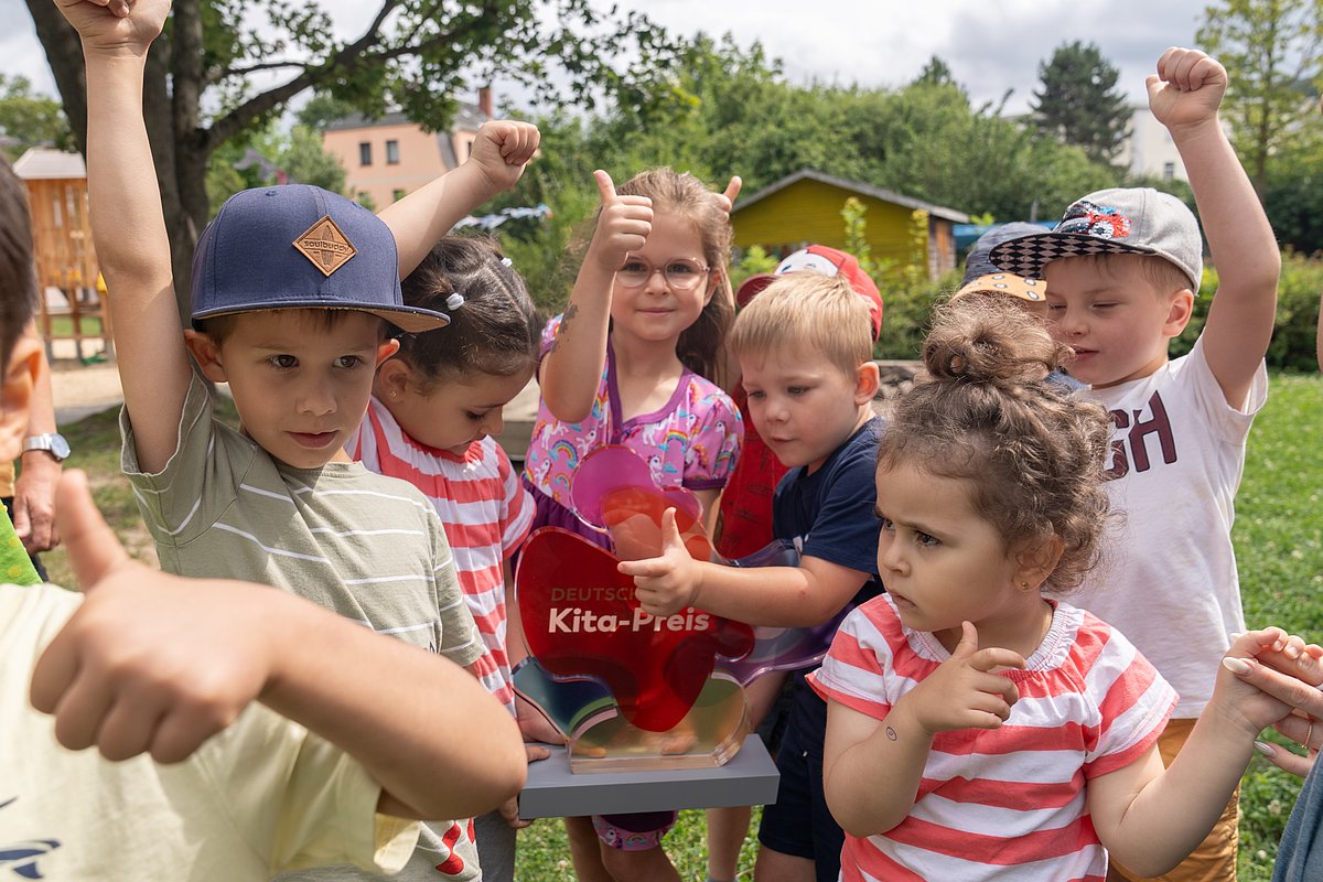 Jubelnde Kita-Kinder mit der Trophäe des Deutschen Kita-Preises 