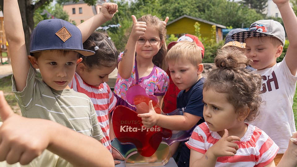 Jubelnde Kita-Kinder mit der Trophäe des Deutschen Kita-Preises 
