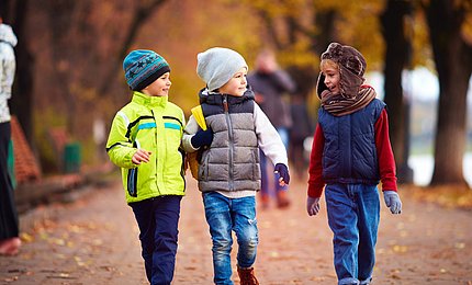 Drei Schulkinder im herbstlichen Park. 