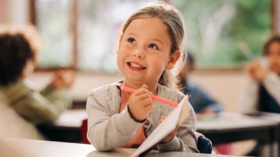 Schulkind zeigt der Lehrkraft ihr Schulheft.