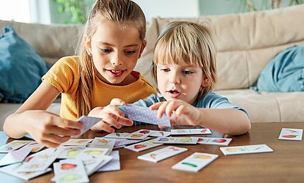 Zwei Kinder spielen mit Memory-Karten.  
