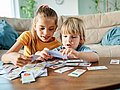 Zwei Kinder spielen mit Memory-Karten.  