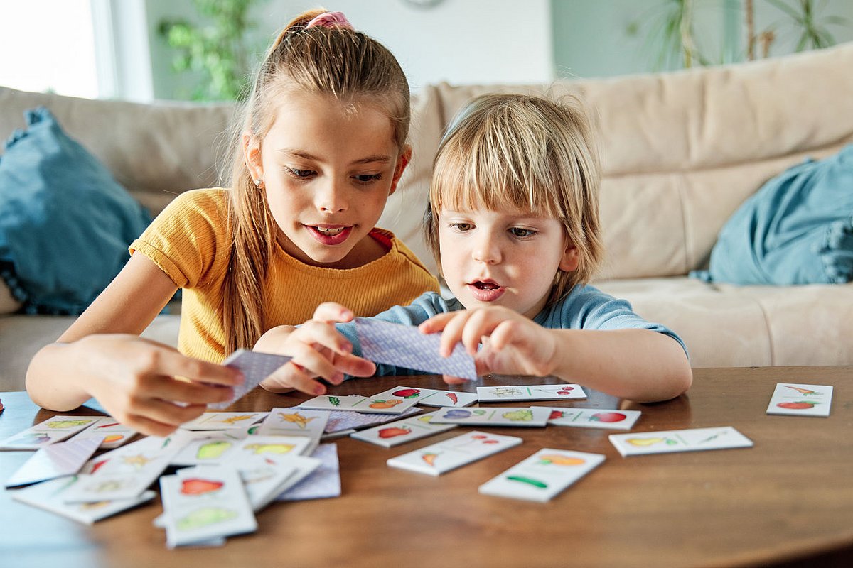 Zwei Kinder spielen mit Memory-Karten.  