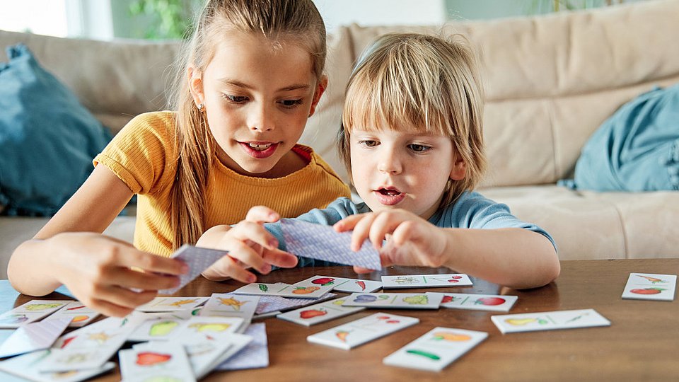 Zwei Kinder spielen mit Memory-Karten.  