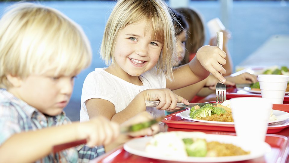 Kinder sitzen an einem Tisch und Essen