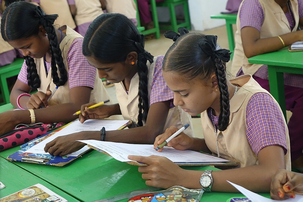 Mädchen sitzen in einer Schulklasse über ihre Bücher gebeugt.