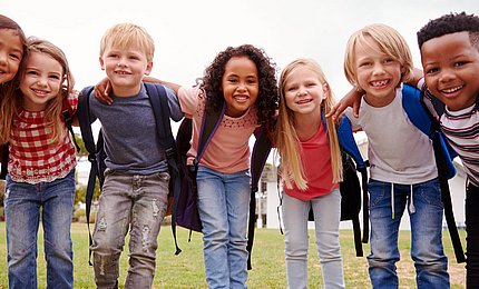 Grundschulkinder lachen in die Kamera. 