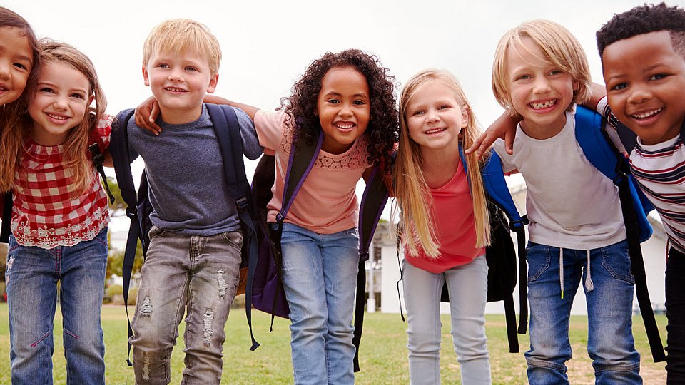 Grundschulkinder lachen in die Kamera. 