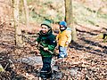 Jungen im Kita-Alter spielen mit Stöcken im Wald. 