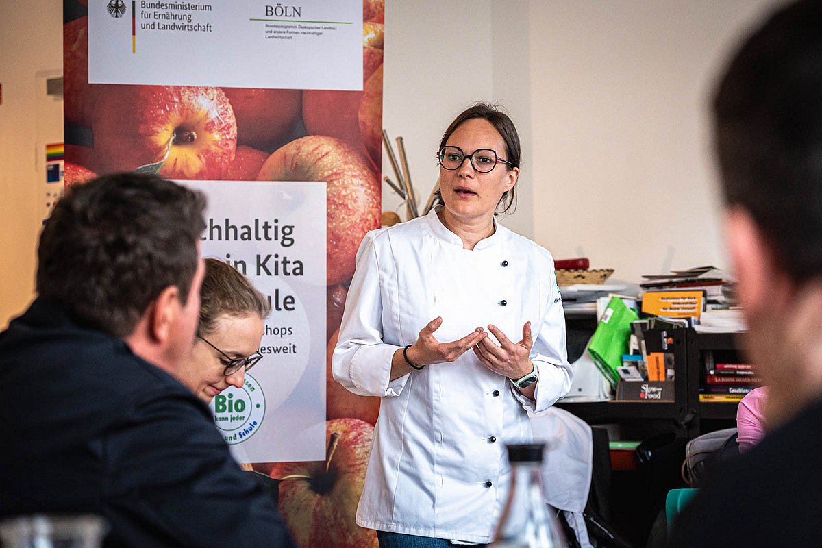 Auf einer Veranstaltung referiert eine Köchin über den Einsatz von Bio-Produkten in der Kita- und Schulverpflegung.