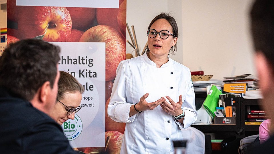 Auf einer Veranstaltung referiert eine Köchin über den Einsatz von Bio-Produkten in der Kita- und Schulverpflegung.