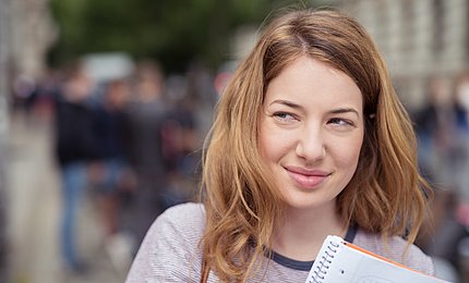 Jugendliche Schülerin hält Schulheft in der Hand. 