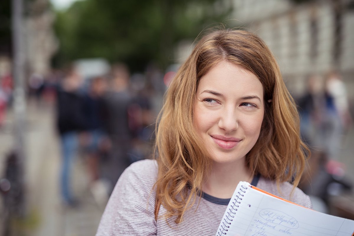 Jugendliche Schülerin hält Schulheft in der Hand. 