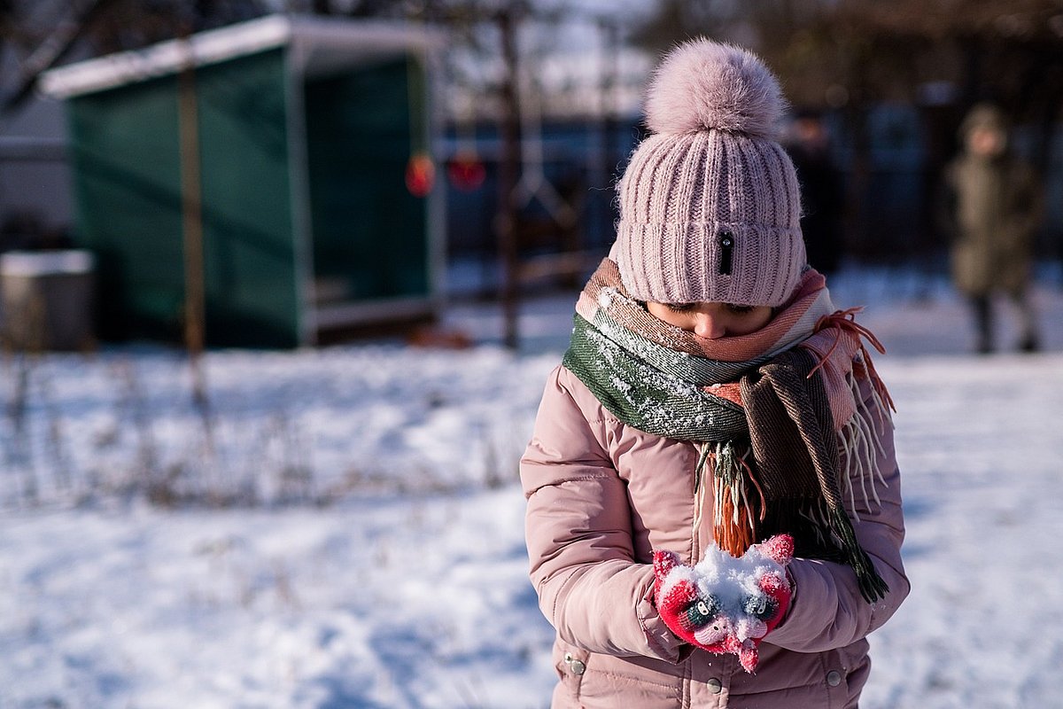 Mädchen spielt im Schnee. 
