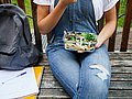 Jugendliche Schülerin hält mitgebrachtes Schulessen auf dem Schoß.  