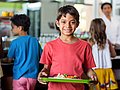 Schulkind in der Schulkantine, auf dem Tablett steht ein Teller mit Schulessen. 