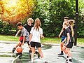 Jugendliche Mädchen und Jungen spielen Basketball.