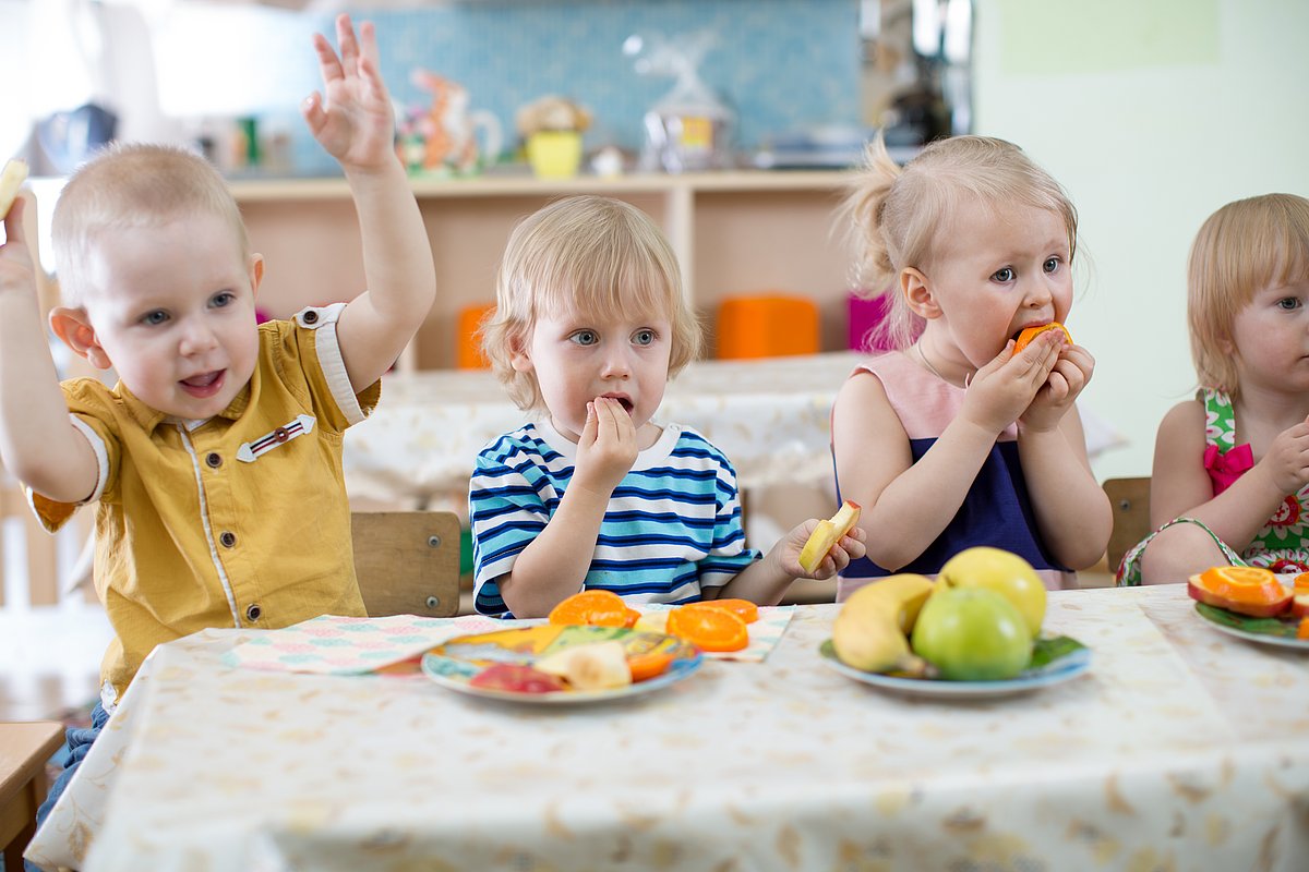 Kitakinder essen gemeinsam an einem Tisch