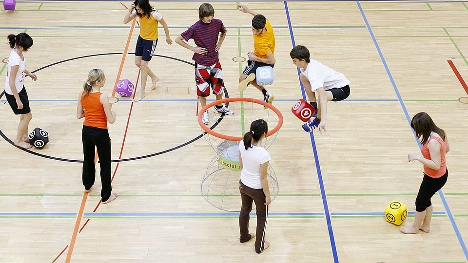 Schulklasse spielt Ballsport in der Sporthalle.