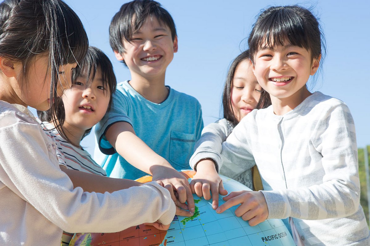 Schulkinder in Japan zeigen auf einem Globus, wo ihr Land liegt.