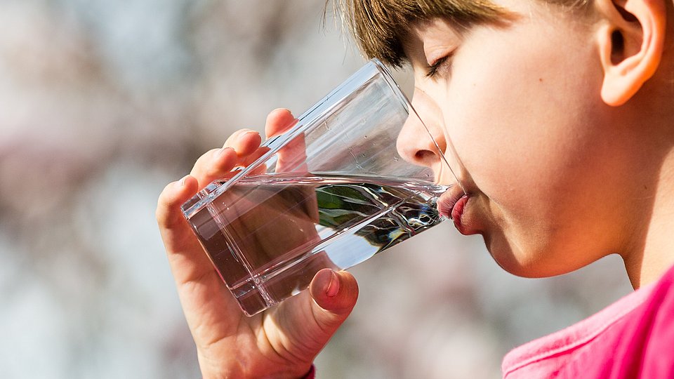 Kind trinkt Wasser aus einem Glas