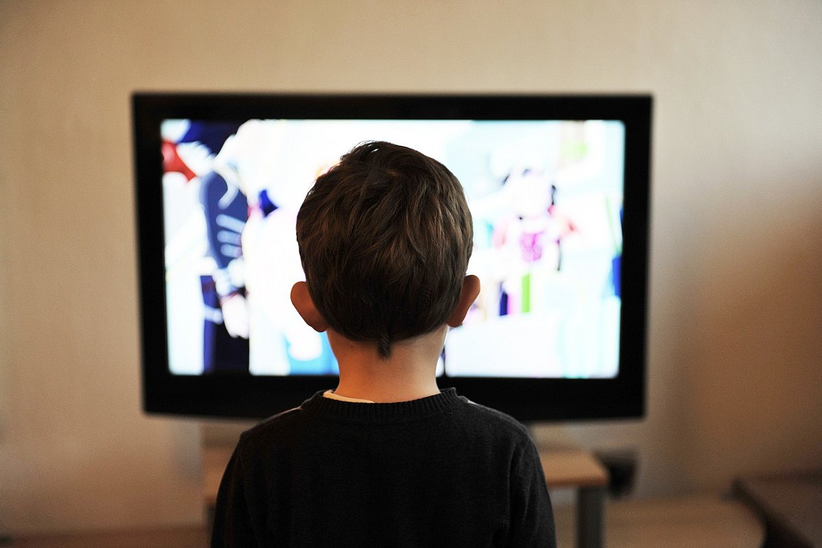 Kind sitzt vor dem Fernseher.