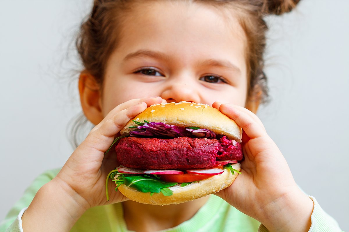 Kita-Kind beißt in Plant-based-Burger.