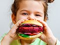 Kita-Kind beißt in Plant-based-Burger.
