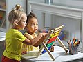 Kita-Kinder spielten an einem Rechenschieber aus Holz.  