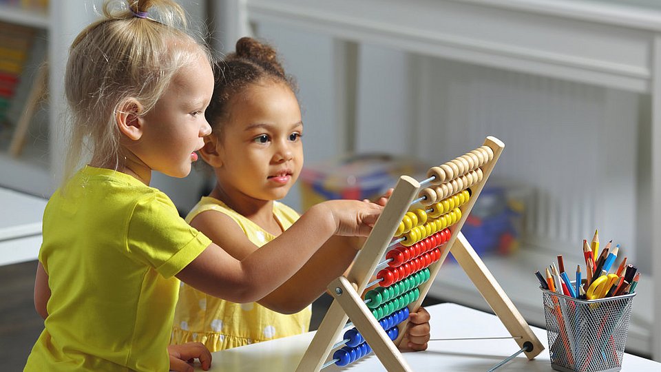 Kita-Kinder spielten an einem Rechenschieber aus Holz.  