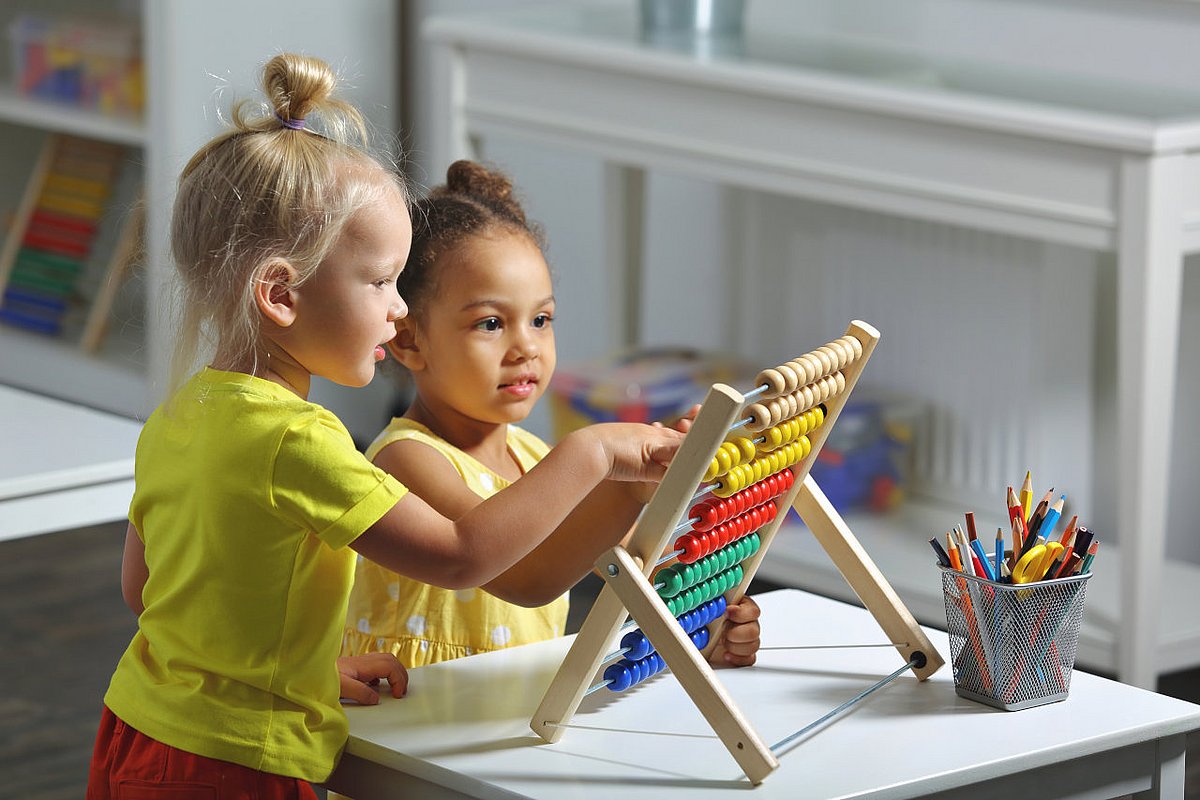 Kita-Kinder spielten an einem Rechenschieber aus Holz.  