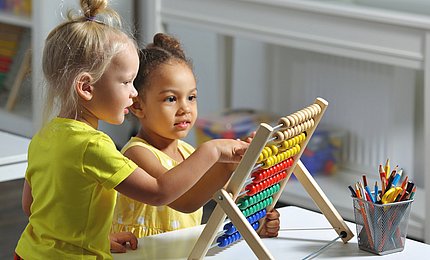 Kita-Kinder spielten an einem Rechenschieber aus Holz.  