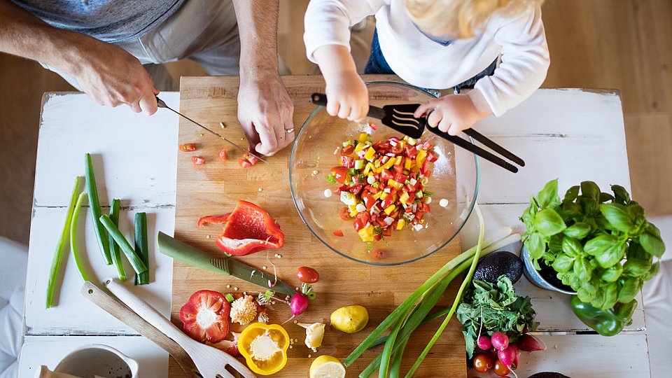 Ein Vater bereitet mit seinem Kind einen Salat zu. 