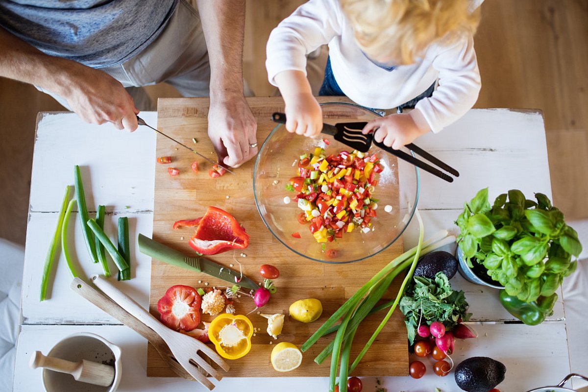Ein Vater bereitet mit seinem Kind einen Salat zu. 