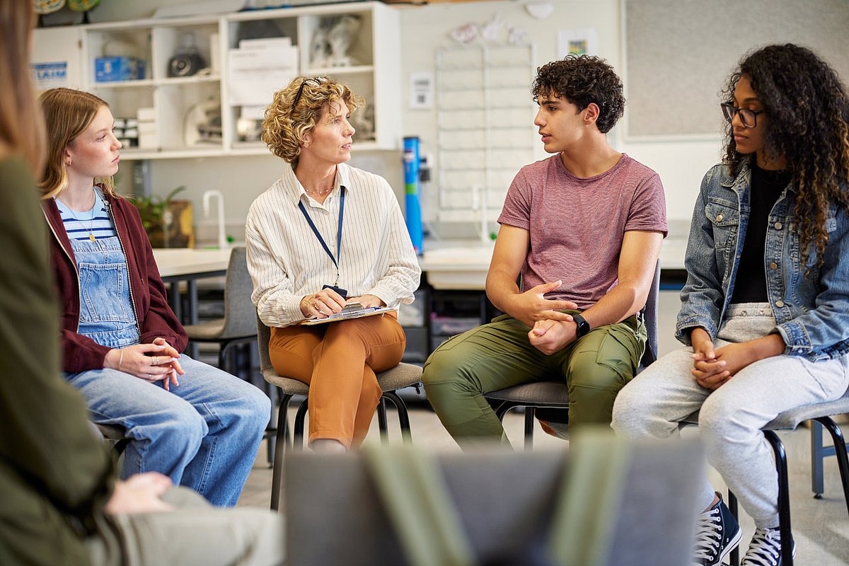 Jugendliche Schüler*innen diskutieren mit einer Lehrerin