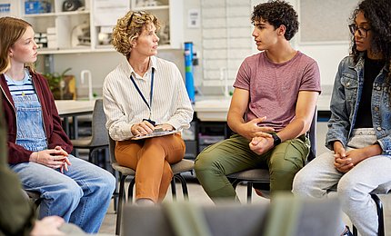 Jugendliche Schüler*innen diskutieren mit einer Lehrerin