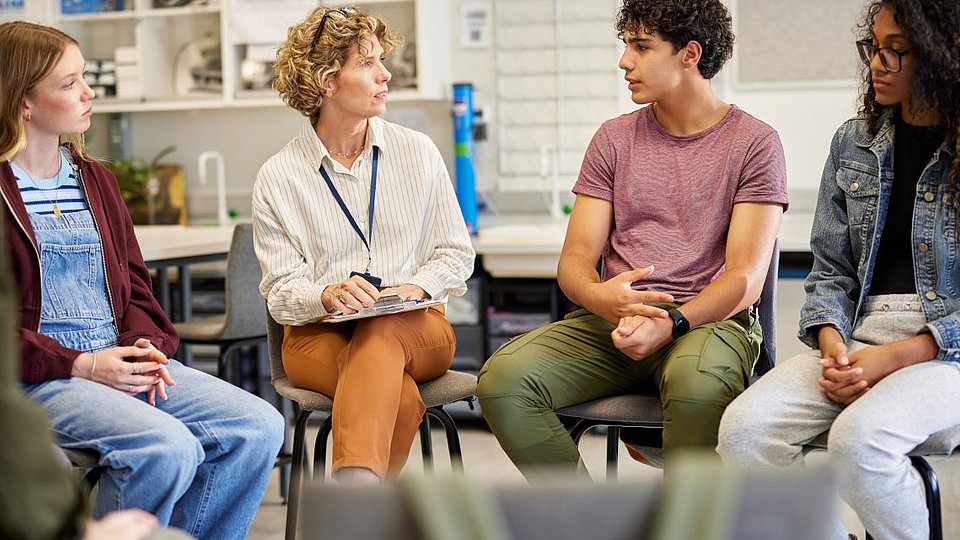 Jugendliche Schüler*innen diskutieren mit einer Lehrerin