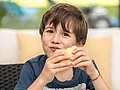 Schuljunge beißt herzhaft in ein Brötchen.