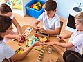 Eine pädagogische Fachkraft spielt mit Kita-Kindern. 