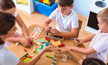 Eine pädagogische Fachkraft spielt mit Kita-Kindern. 